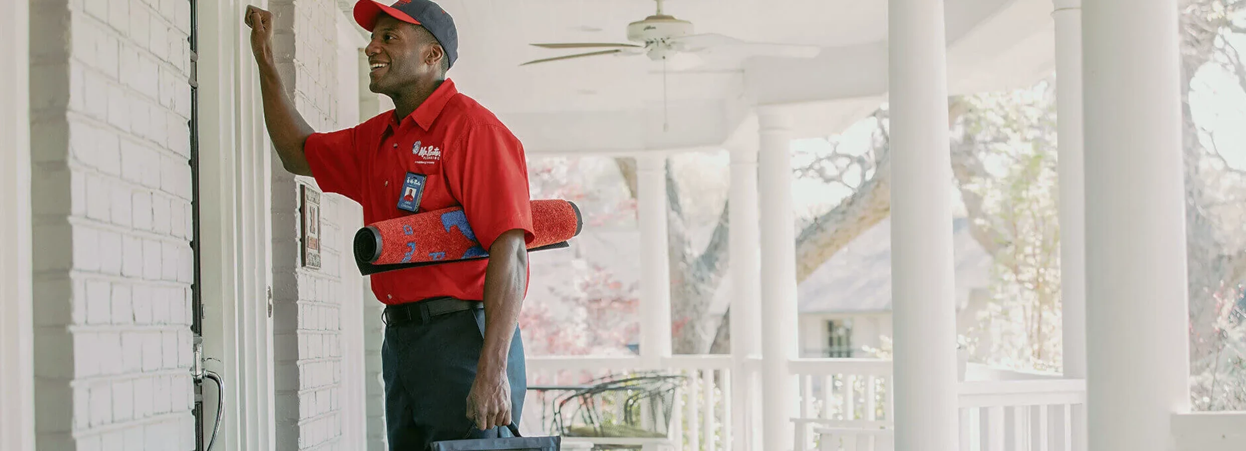 Smiling male African American Mr. Rooter employee knocking on the door of a customer's home.