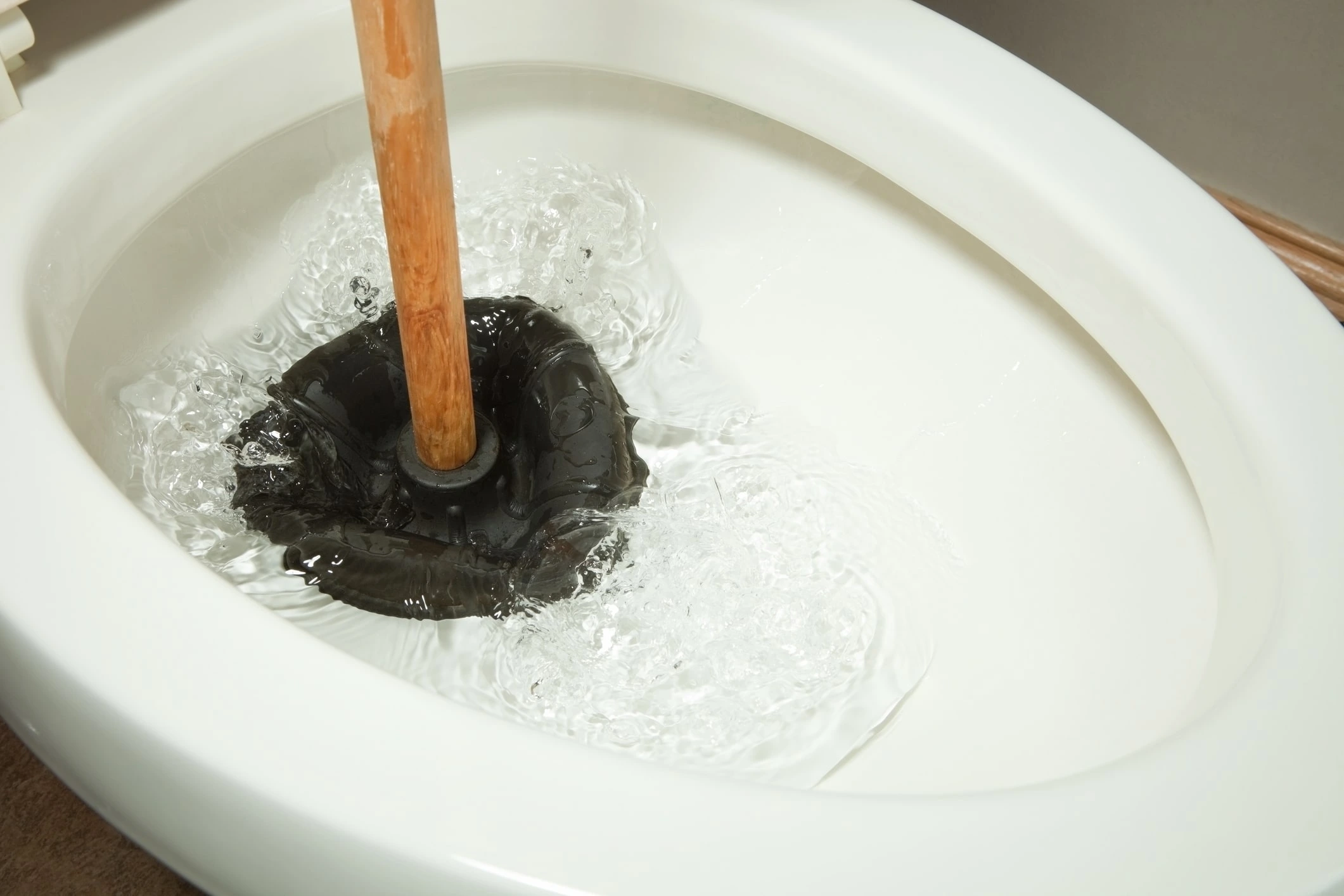 A plunger working to clear a clogged toilet drain