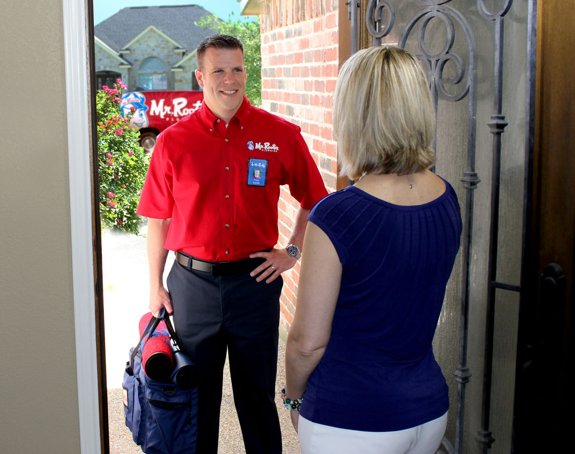 Mr. Rooter technician greeting customer at front door.