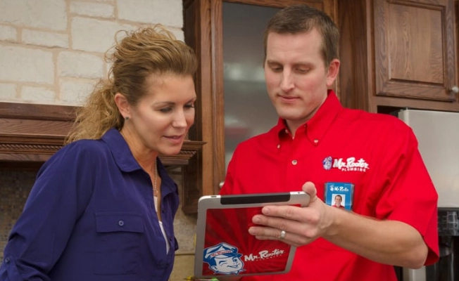 A plumber using an electronic tablet to show a woman information about tankless water heater installation in Waco, TX.