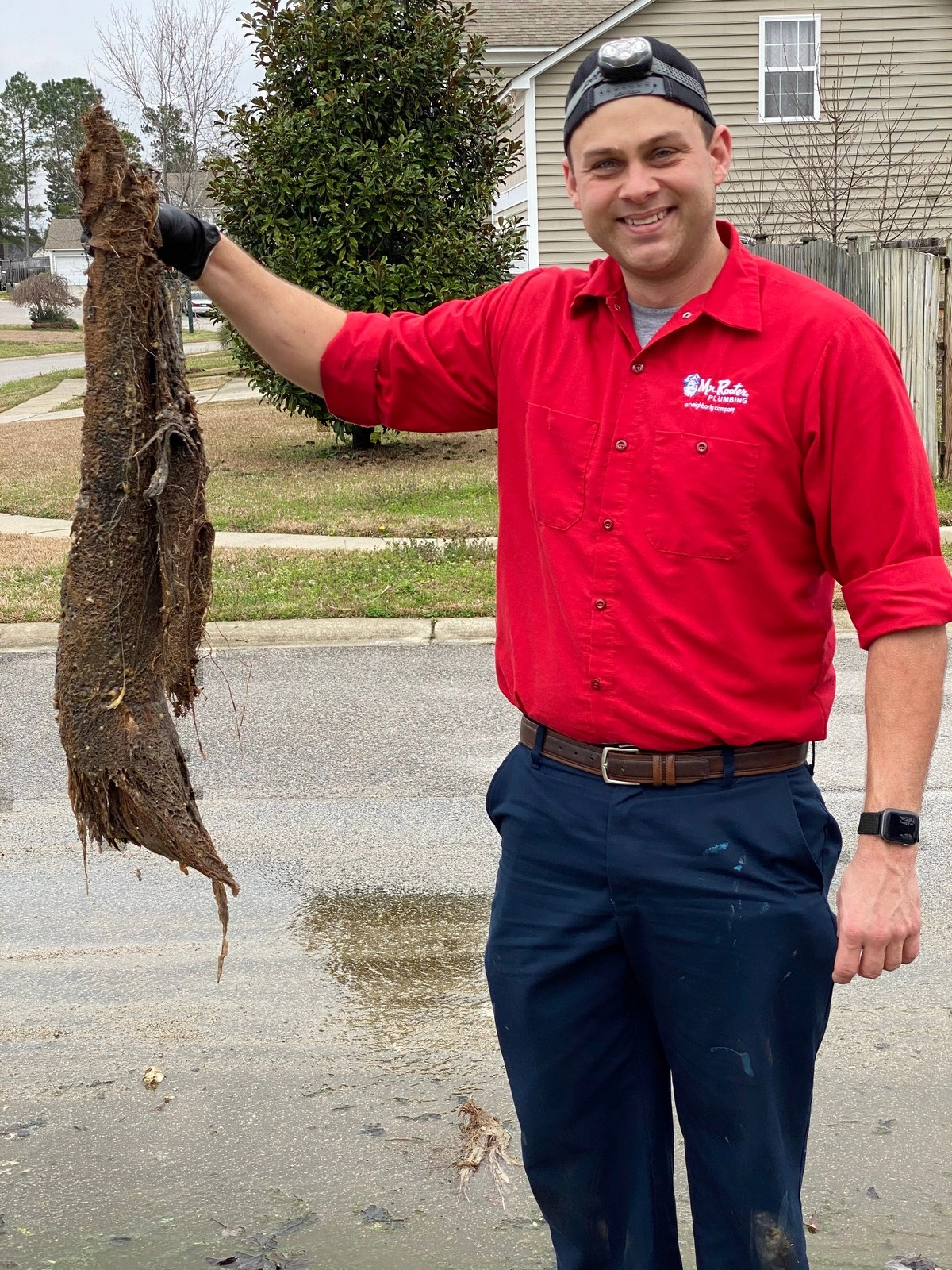 Mr. Rooter Plumbing technician holding tree roots extracted from a blockage in Cayce, SC