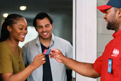 Mr. Rooter technician smiling while handing business card to woman and man at their front door.