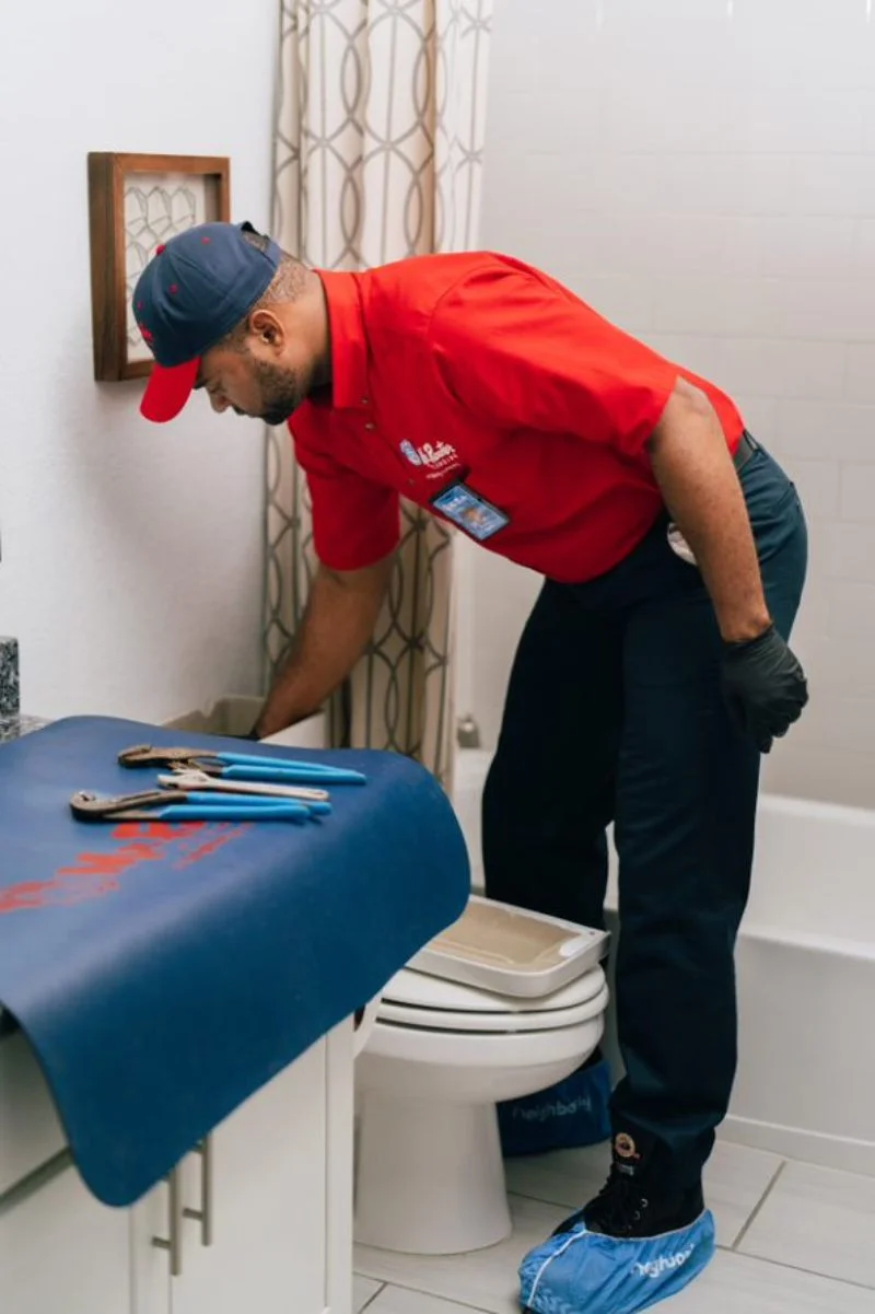 Mr. Rooter service professional inspecting a toilet tank .