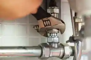 A Sarasota plumber with a wrench fixing a pipe under a sink