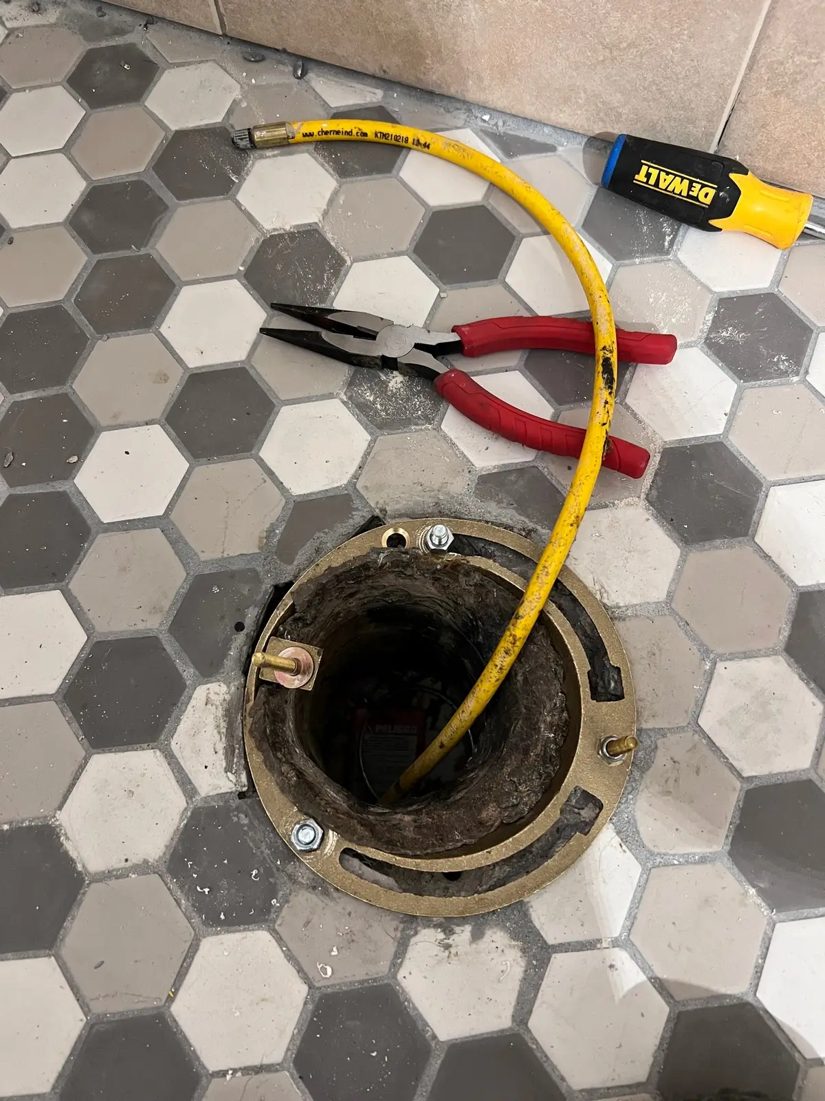 An open drain cover with a long sewer snake inserted into the hole for sewer line cleaning in San Antonio.