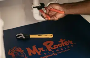 Hand fixing pipe over Mr. Rooter rug during Prescott residential plumbing service