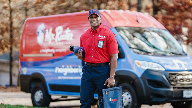 Mr. Rooter plumber standing in front of a van.