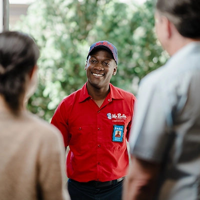 Mr. Rooter professional greeting customer's at their front door.