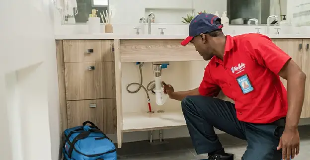 Mr. Rooter plumber fixing a pipe under a sink.