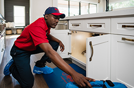 Mr. Rooter professional working under a sink.