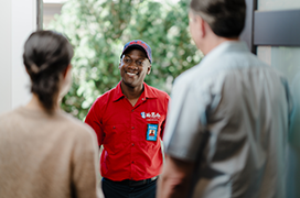 Mr. Rooter professional greeting two customers at their front door.