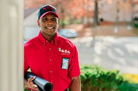 Smiling Mr. Rooter professional at a customer's front door.