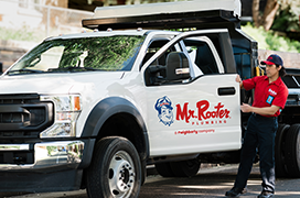 Mr. Rooter professional standing outside of a white branded work truck.