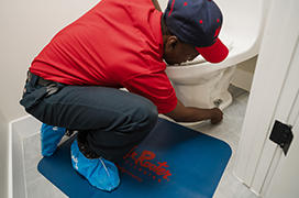 Mr. Rooter professional fixing a toilet.