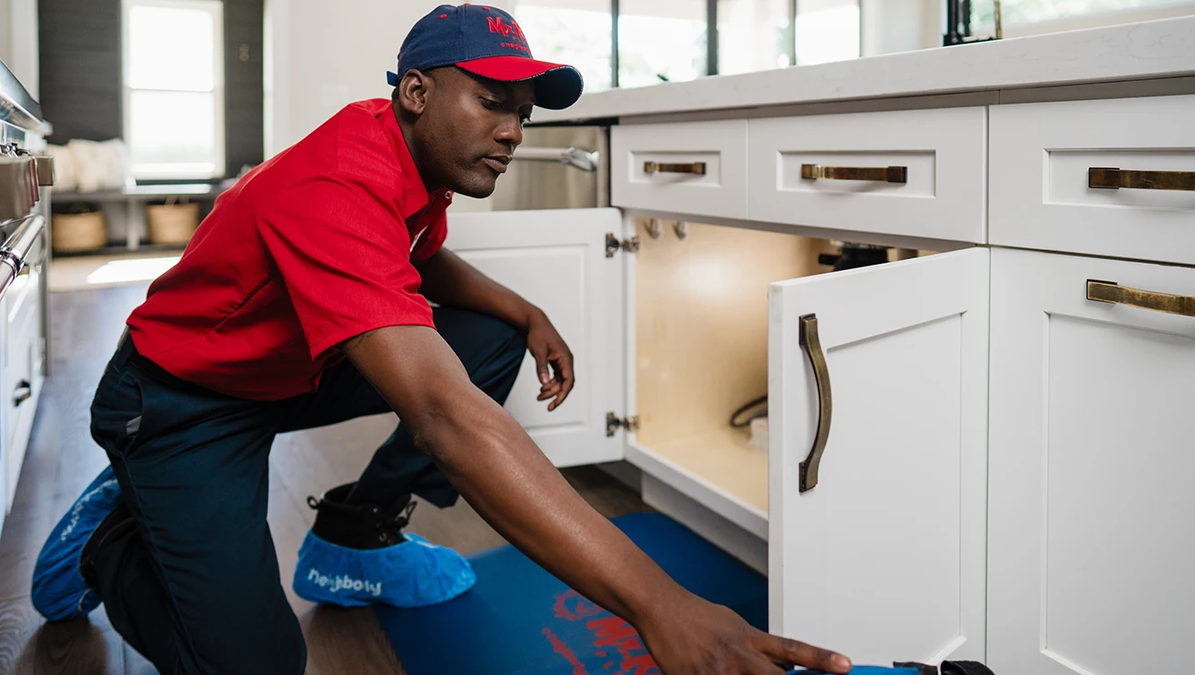 Mr. Rooter professional working underneath a sink.