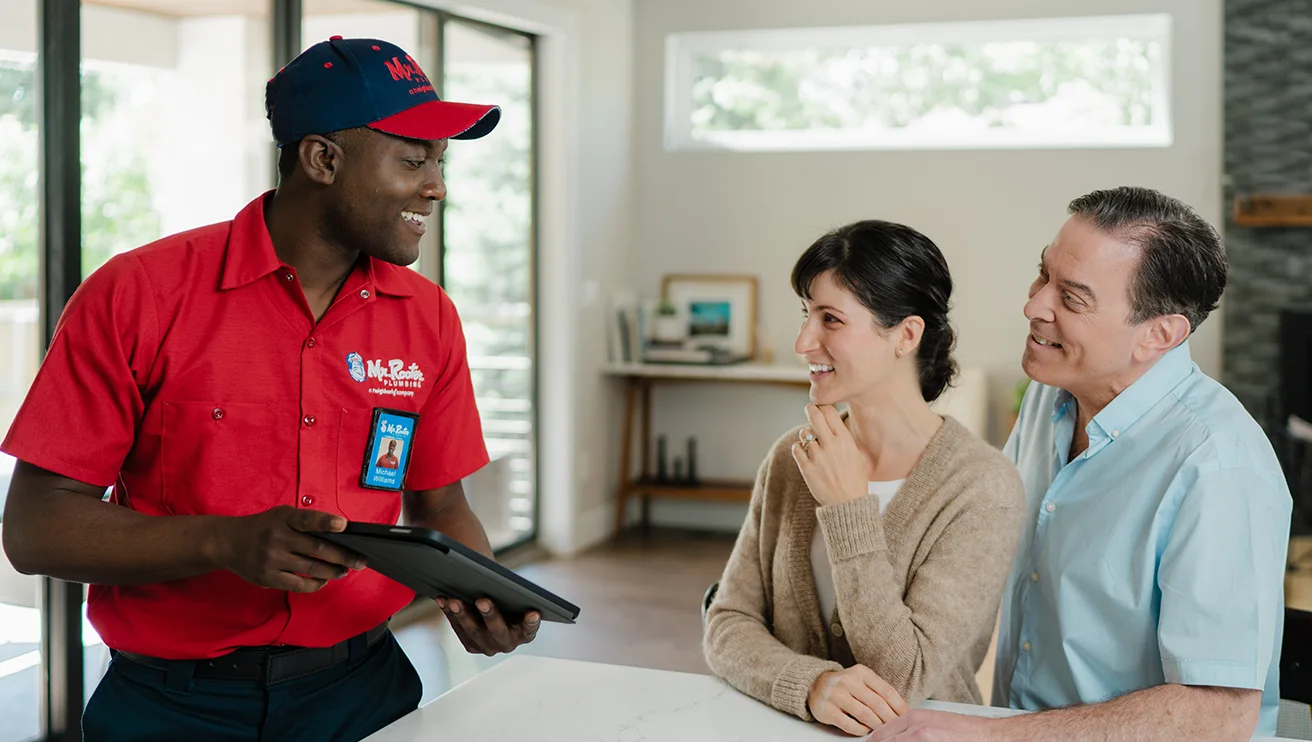 Mr. Rooter technician showing customers a service plan on a tablet.