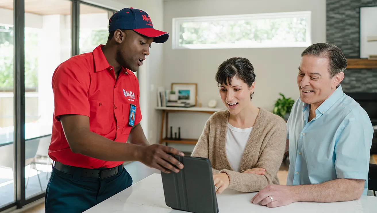 Mr. Rooter technician explaining service options to two customers.