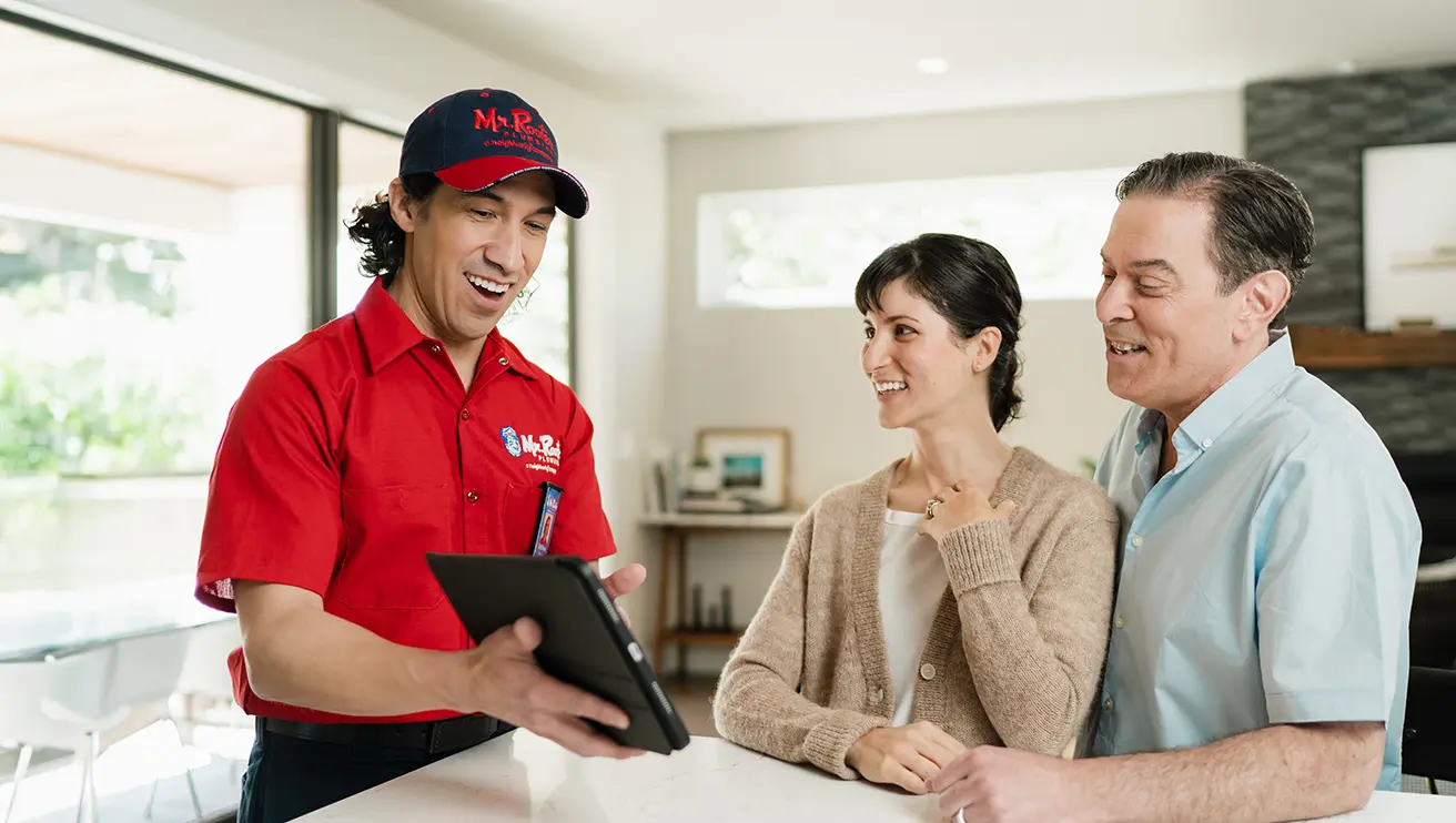 Mr. Rooter technician showing customers service options on a tablet.