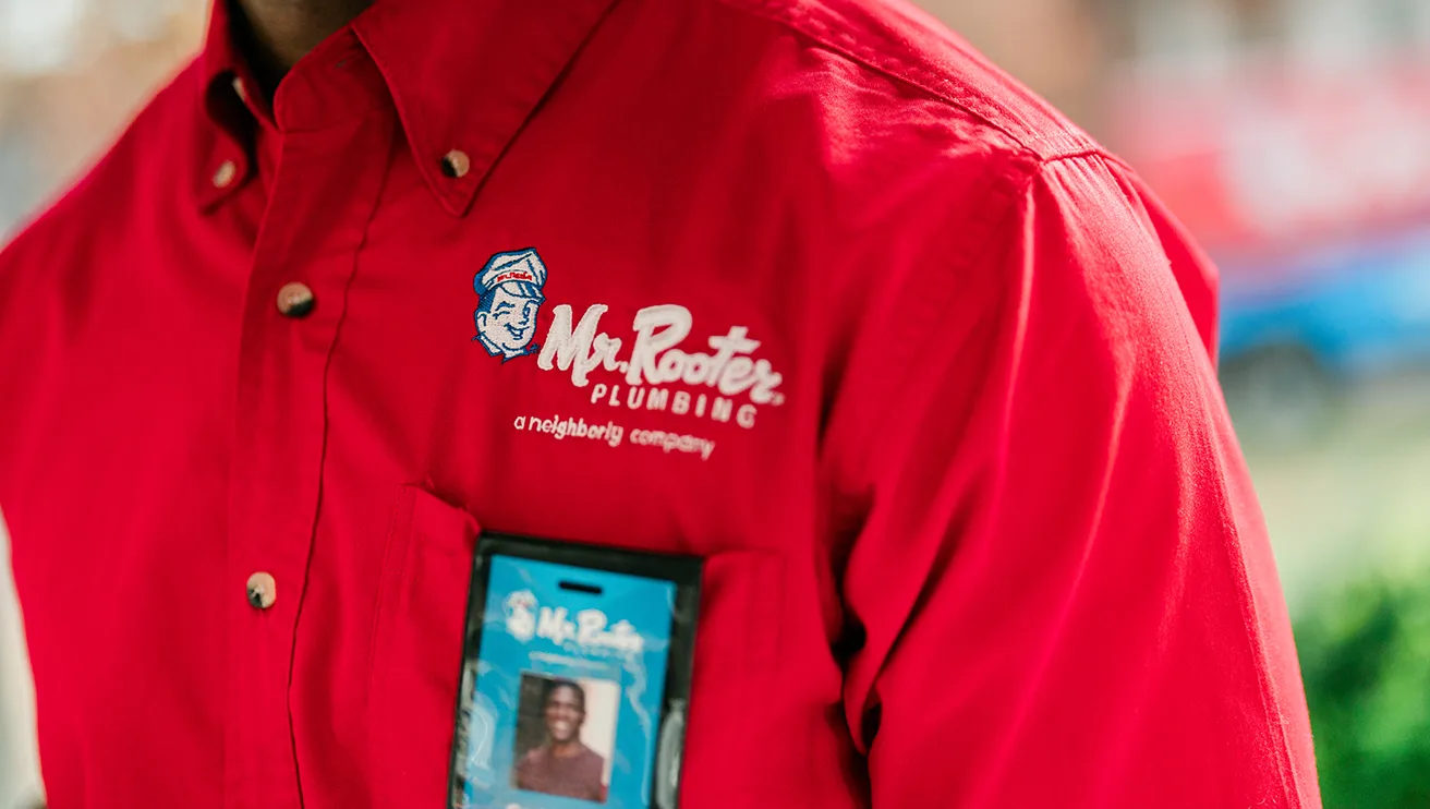 Close up of a Mr. Rooter logo on a professional's red company shirt.