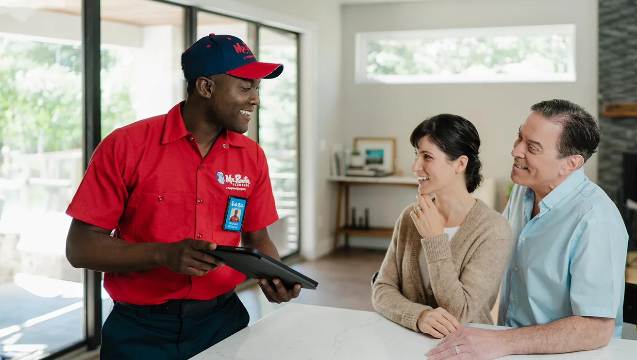 Mr. Rooter technician working with two customers.