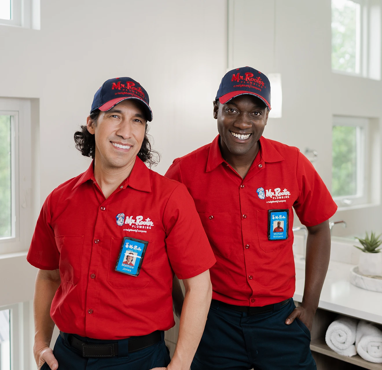 Two Mr. Rooter technicians standing in a modern bathroom.