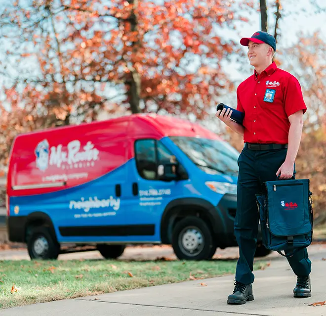 Mr. Rooter professional walking up to a home with a branded van in the background.