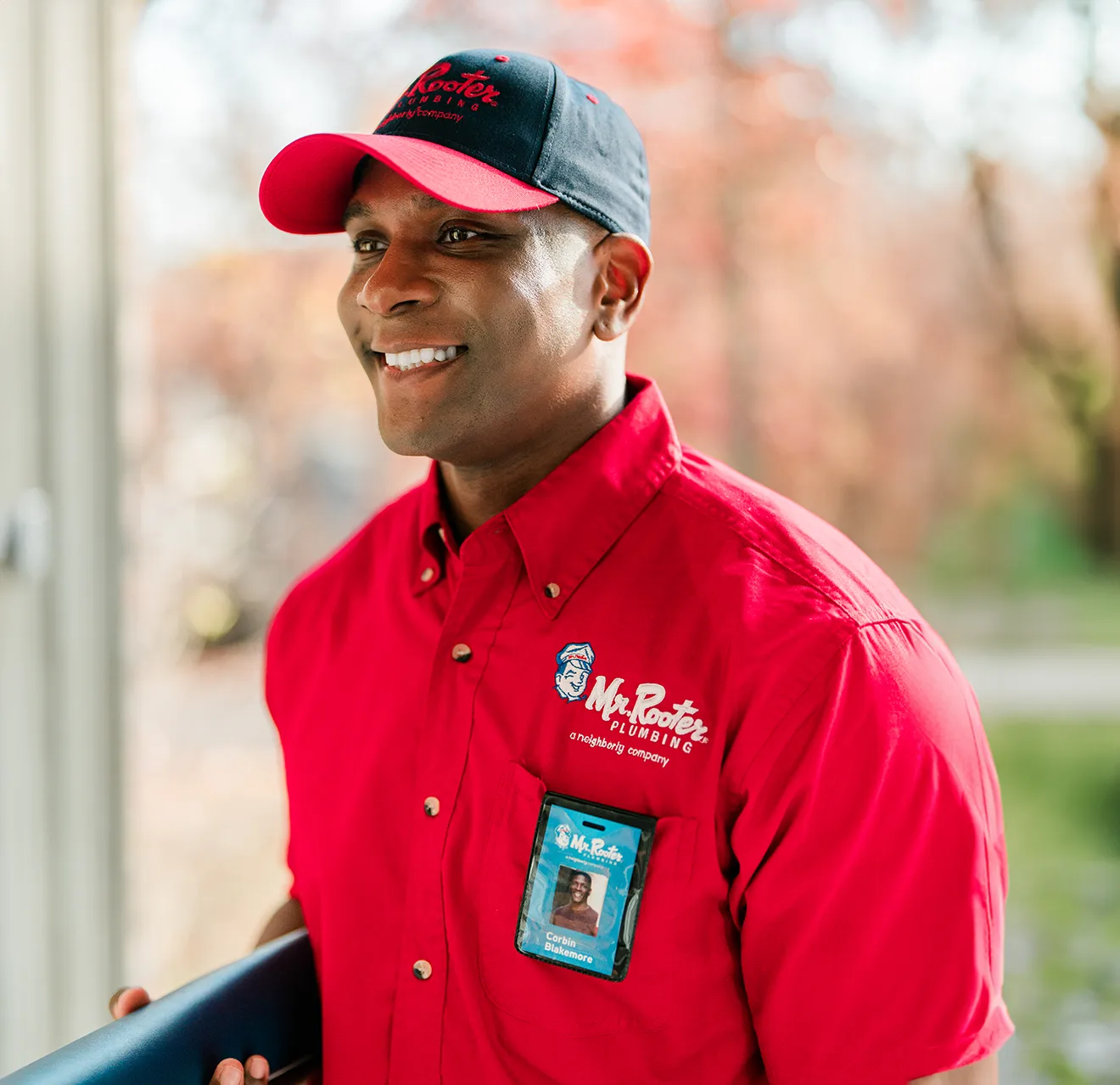 Smiling Mr. Rooter technician entering a customer's home.