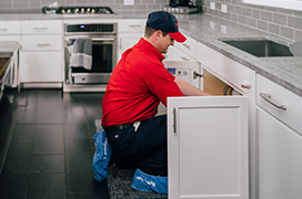 Mr. Rooter professional working underneath kitchen counter.