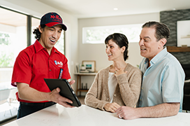 Mr. Rooter professional speaking with two customers and showing them something on a tablet.