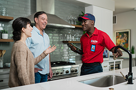 Mr. Rooter professional speaking with two customers in their kitchen.