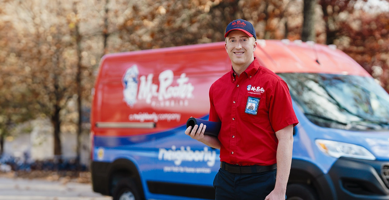 Mr. Rooter professional standing beside a branded work van.