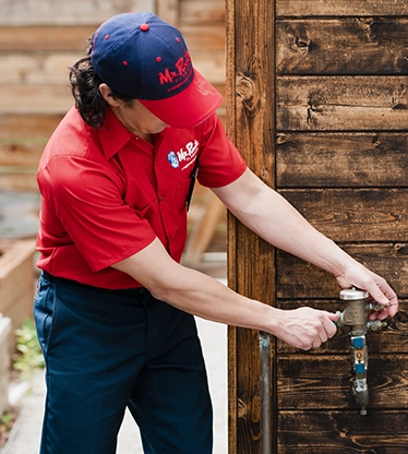 Mr. Rooter Plumbing professional turning on a water spigot.