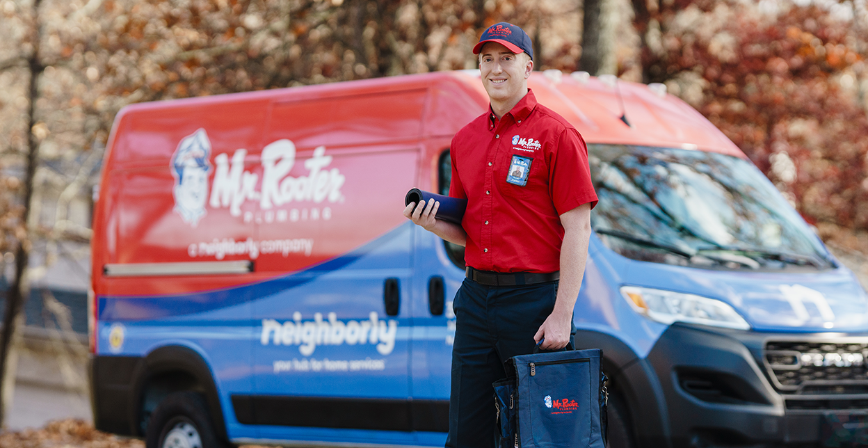 Mr. Rooter professional standing in front of a branded van.