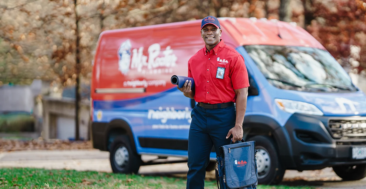 Mr. Rooter technician standing beside a branded work van.