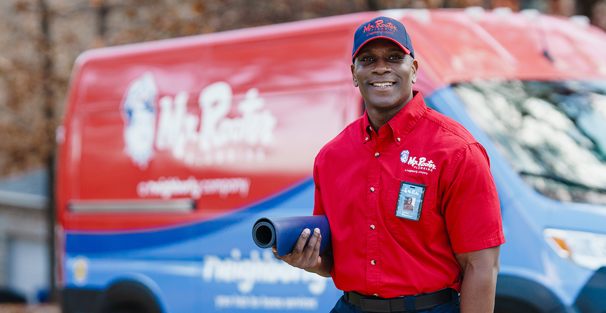 Mr. Rooter technician standing beside a branded van.