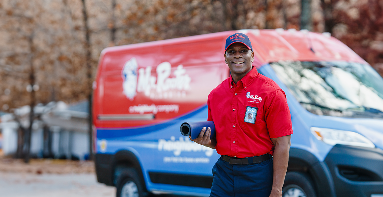 Mr. Rooter professional standing in front of a branded van.