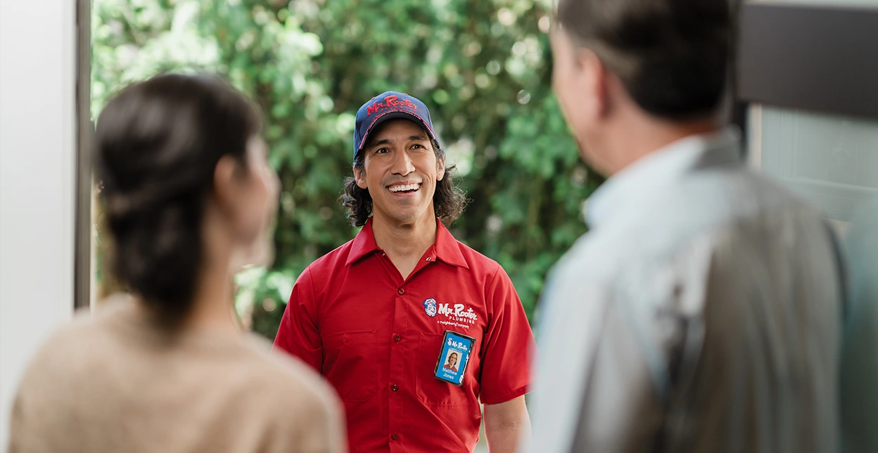 Two customers greeting a Mr. Rooter professional their front door.