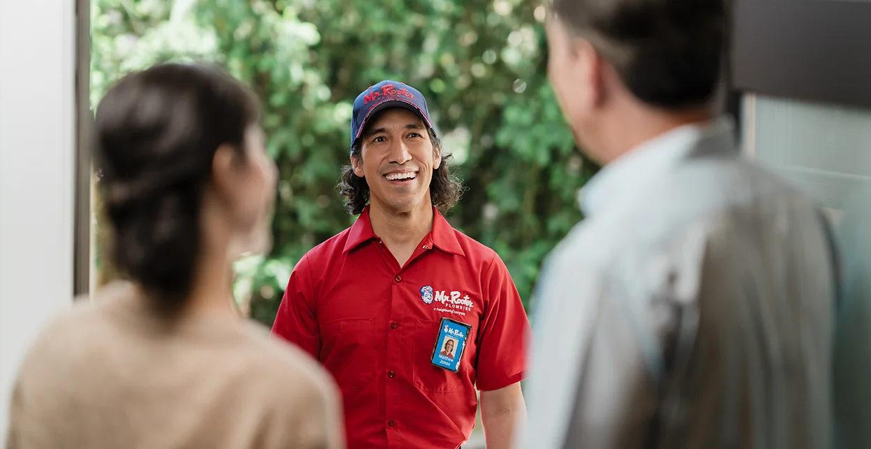 Smiling Mr. Rooter technician greeting customer's at their door.