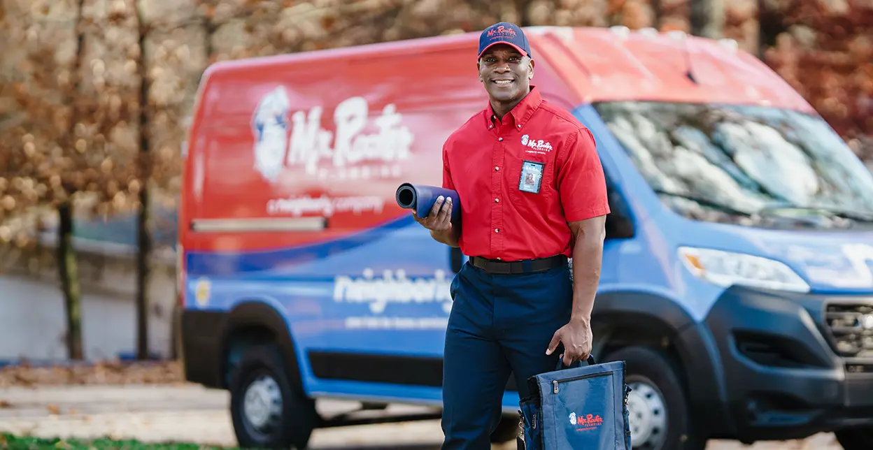 Mr. Rooter employee standing beside a branded work van.