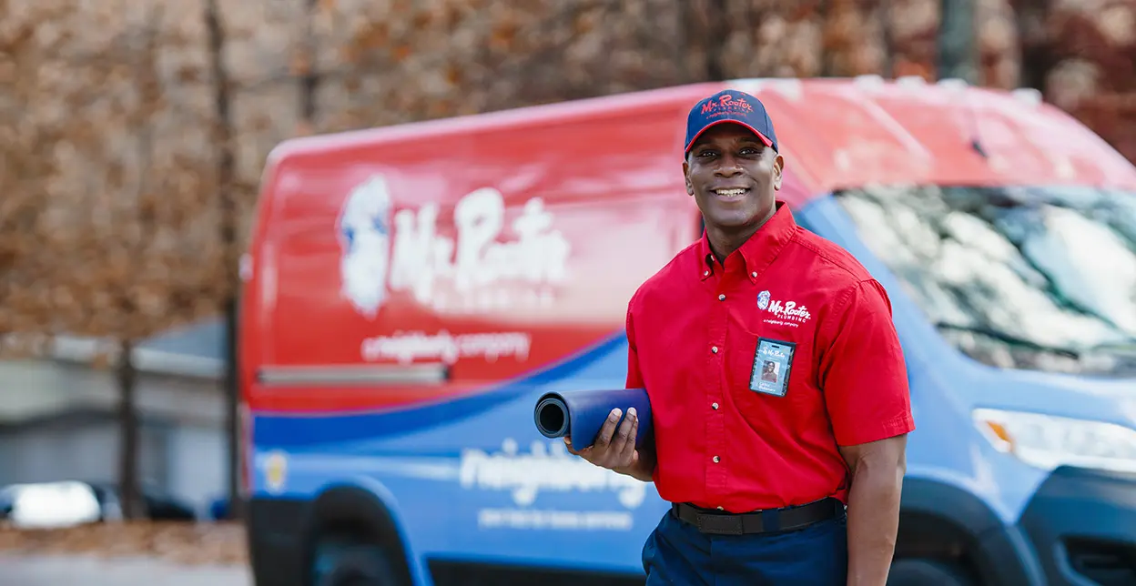 Mr. Rooter technician standing in front of a branded work van.