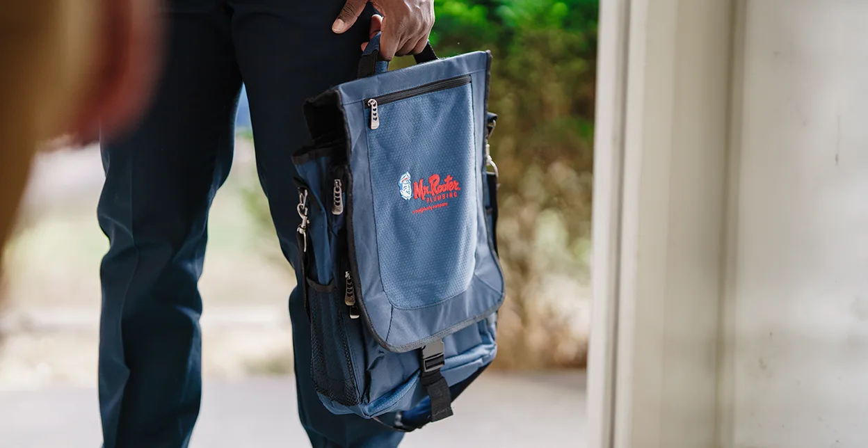 Mr. Rooter techician carrying a supply bag.