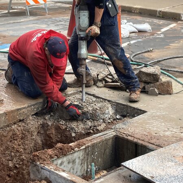 2 Mr. Rooter employees working on getting up some concrete