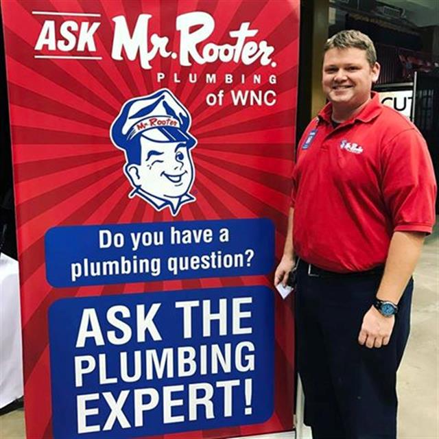 A Mr. Rooter technician beside the banner