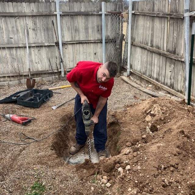 Mr. Rooter employee using a tool that is in a hole.