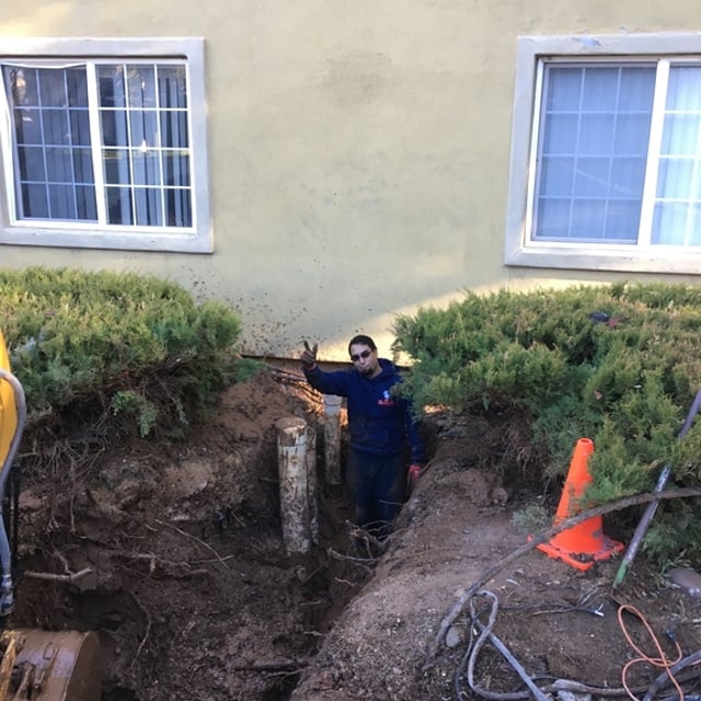 Person in a dug out ditch to get to piping