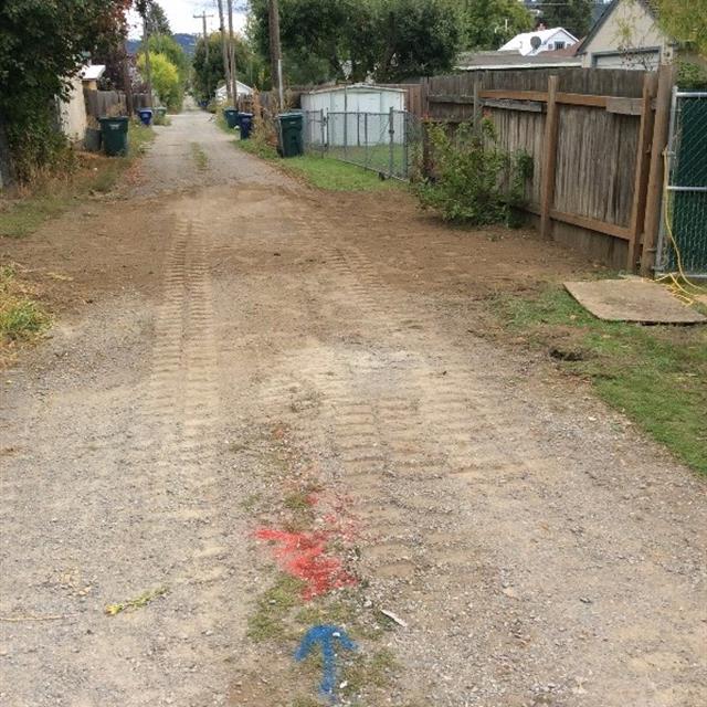 Dirt road with tire tracks and spray paint indicating location of plumbing.