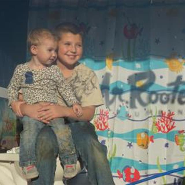 Two little kids sitting in front of a wall painted mr Rooter