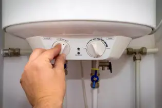 Person turning off a water heater.