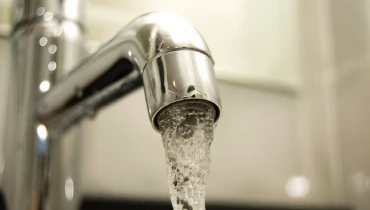 Close-up of water coming from a stainless steel faucet.