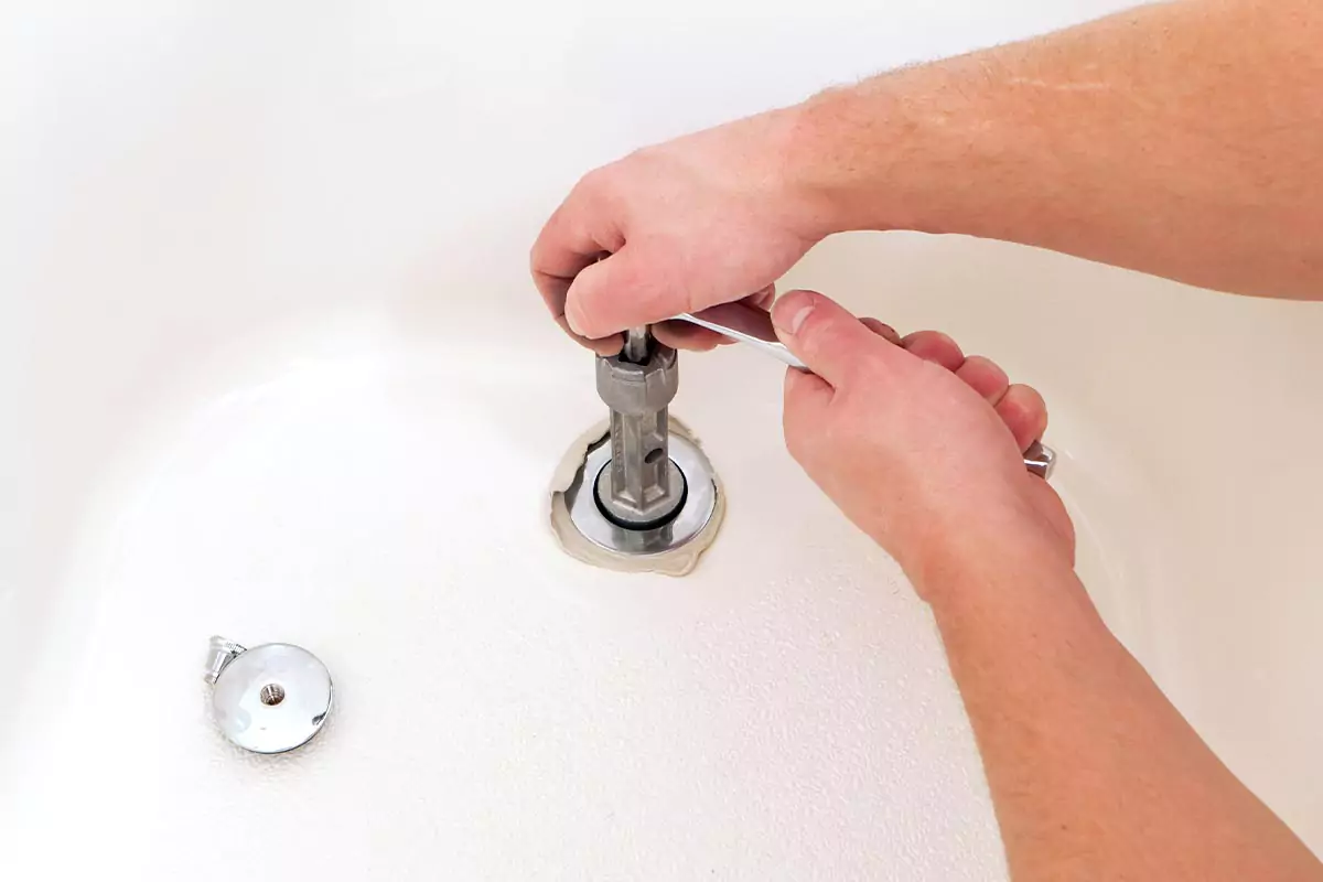 Someone removing a bathtub drain.